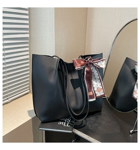 Close-up of black PU leather tote bag with decorative printed silk scarf on the side