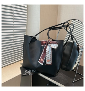 Detail of black matte tote bag featuring a decorative silk scarf on the handle with mirror view