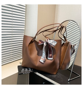 Detail of large brown leather tote bag with a patterned scarf handle and spacious interior