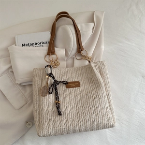 Chic woven straw bucket tote with brown leather handles and decorative tennis racket charm