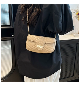 Detail of beige quilted shoulder bag with V-shaped stitching and gold twist lock