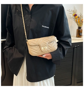 Close-up of beige quilted leather handbag featuring a gold turn-lock and V-shape stitching