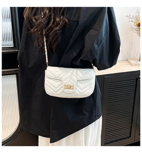 Detail of white V-quilted faux leather bag featuring a gold metal twist lock and chain strap
