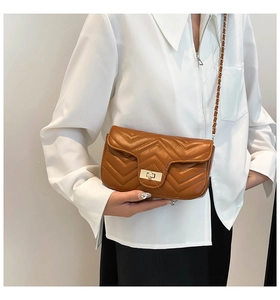 Details einer braunen Stepptasche aus Leder mit goldenem Drehverschluss und Kettenriemen
