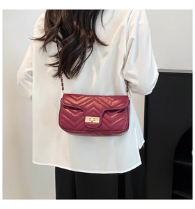 Detail of red chevron quilted crossbody bag with gold chain strap and twist lock
