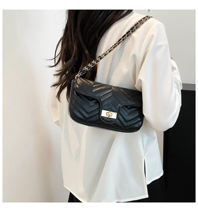Detail of black quilted leather shoulder bag with gold chain strap and turn-lock closure