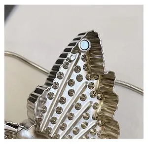 Detail of butterfly-shaped metal magnetic clasp and silver snake chain on a bag