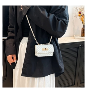 Close-up of white quilted mini bag featuring golden square twist lock and chain strap