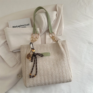 Beige woven bucket tote bag with grass green leather handles and a tennis racket charm
