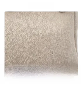 Close-up of litchi grain leather texture and fashion debossed lettering on beige bucket bag