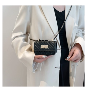 Detailed close-up of a mini quilted black chain bag with a gold square lock on a model