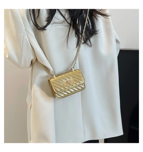 Close-up of a quilted gold mini crossbody bag with a twist-lock and chain strap