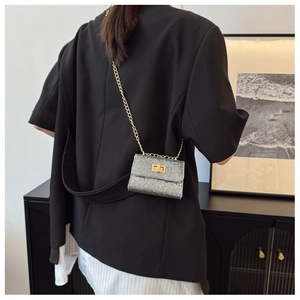 Detail of silver sequin mini bag with golden chain strap and twist lock on a model