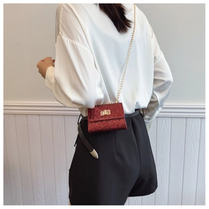 Detail of red glitter mini crossbody bag with golden chain strap and metallic lock