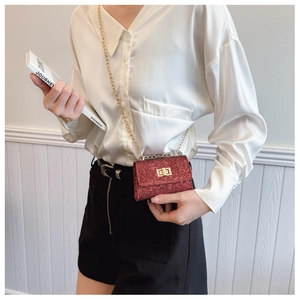 Detail of red sequin mini crossbody bag with gold chain strap on white shirt outfit
