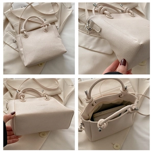 Detail view of beige lychee leather bucket bag with knot handle and interior compartments