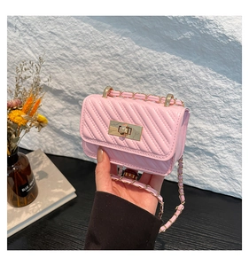 Macro detail of mini pink quilted chain bag with gold twist lock and glossy finish