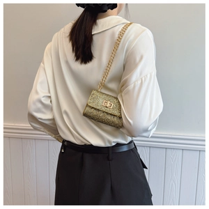 Detail of gold sequin mini crossbody bag with metal chain strap and turn-lock closure
