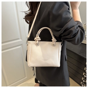 Detail of cream leather bucket bag with knot handle and premium lychee texture