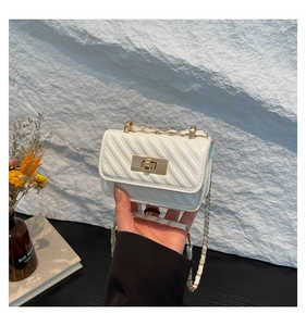 Detailed close-up of white quilted mini square bag with golden twist lock and chain strap