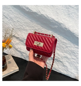Detail of red quilted chain mini bag with gold twist lock held by a model