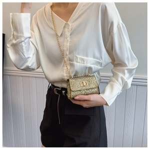 Close-up of a gold sequin mini crossbody bag with metal chain strap and twist-lock
