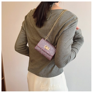 Detail of sparkly purple rhinestone mini bag featuring golden chain and metal turn-lock