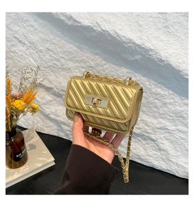 Detail of gold mini quilted chain bag with elegant metallic twist lock in hand