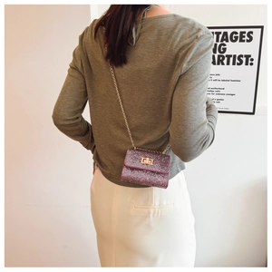 Macro view of purple crossbody bag with shiny glitter finish and golden chain strap