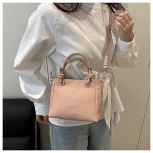 Détail d'un sac seau rose clair en cuir grainé avec poignée et bandoulière amovible