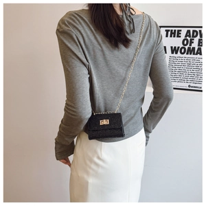 Model view showing the back profile of a compact black sequin crossbody bag with chain