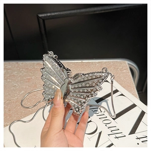 Detailed view of a silver butterfly-shaped evening bag with sparkling rhinestones and chain