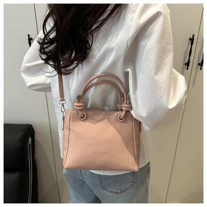 Sac seau en cuir grainé rose avec détail de poignée nouée porté en bandoulière sur modèle