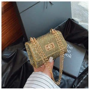 Detail view of a luxury gold sequin crossbody bag with a metal twist lock and chain strap
