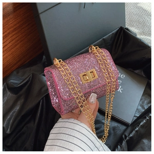 Detail of pink sequin crossbody bag featuring a golden chain strap and metallic twist lock