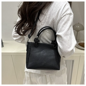Détail d'un sac seau noir en cuir grainé avec poignées nouées et boucles en métal argenté