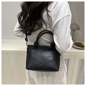 Litchi texture black square bag shown with a knotted handle and crossbody strap