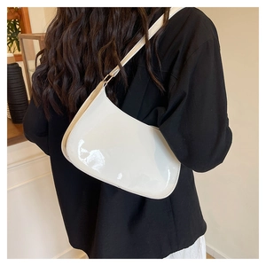 Glanzende witte lakschouder-tas getoond op een model in een modern interieur