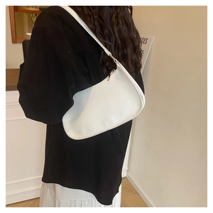 Detail van witte glanzende laklederen baguette tas met minimalistische gouden ritssluiting