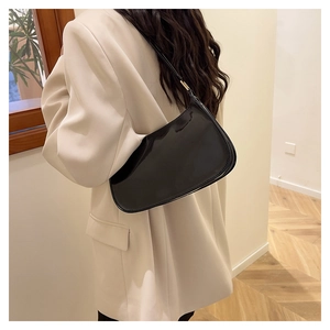 Glossy black patent leather baguette shoulder bag styled with a beige blazer outfit
