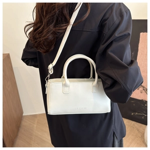 Dettaglio del modello che indossa la borsa a tracolla bianca minimalista con manici superiori