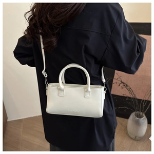 Vue détaillée d'un petit sac blanc en cuir avec logo FASHION porté sur une chemise noire