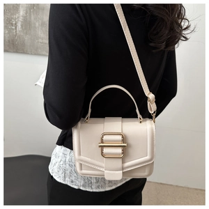 Detail of minimalist beige crossbody bag featuring gold buckle and textured finish