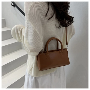 Detail of vintage brown crossbody bag with dual handles and embossed fashion text