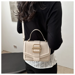 Detailed view of cream leather crossbody bag featuring gold hardware and elegant top handle