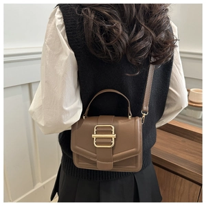 Detail of a brown vintage leather handbag with gold metal buckle shown on a model