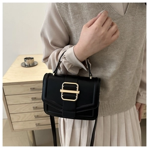 Detail of minimalist black crossbody bag with premium gold buckle and matte leather texture