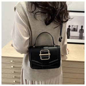 Model view of black leather crossbody bag with gold buckle and adjustable strap