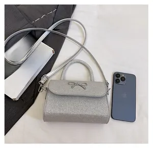 Close-up of glitter silver mini handbag with metallic bow showing size relative to phone