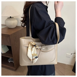 Detail of minimalist khaki tote bag with a decorative printed scarf on the handle